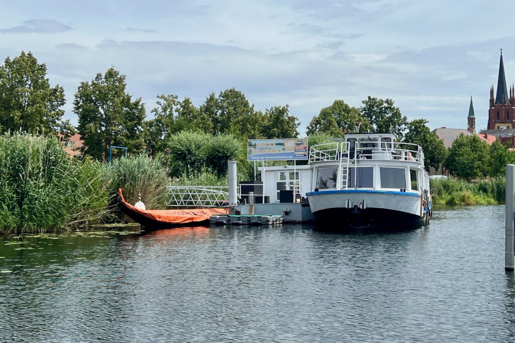 Der Anleger für Fahrten mit dem Ausflugsschiff und der Gondel vor der Inselbrücke in Werder (Havel). Im Hintergrund die Kirche