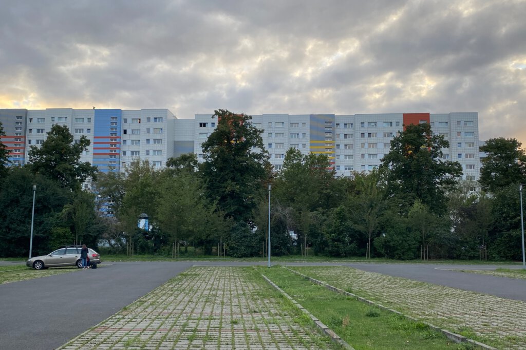 Blick auf den Parkplatz am Tierparkeingang Schloss Friedrichsfelde. Im Hintergrund Plattenbauten.