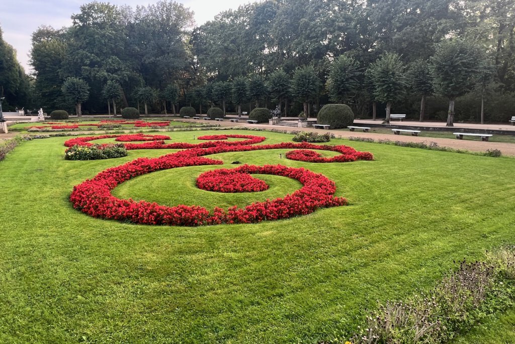 Rote Blumenrabatten, umgeben von grünem Rasen, vor dem Schloss Friedrichsfelde in Berlin
